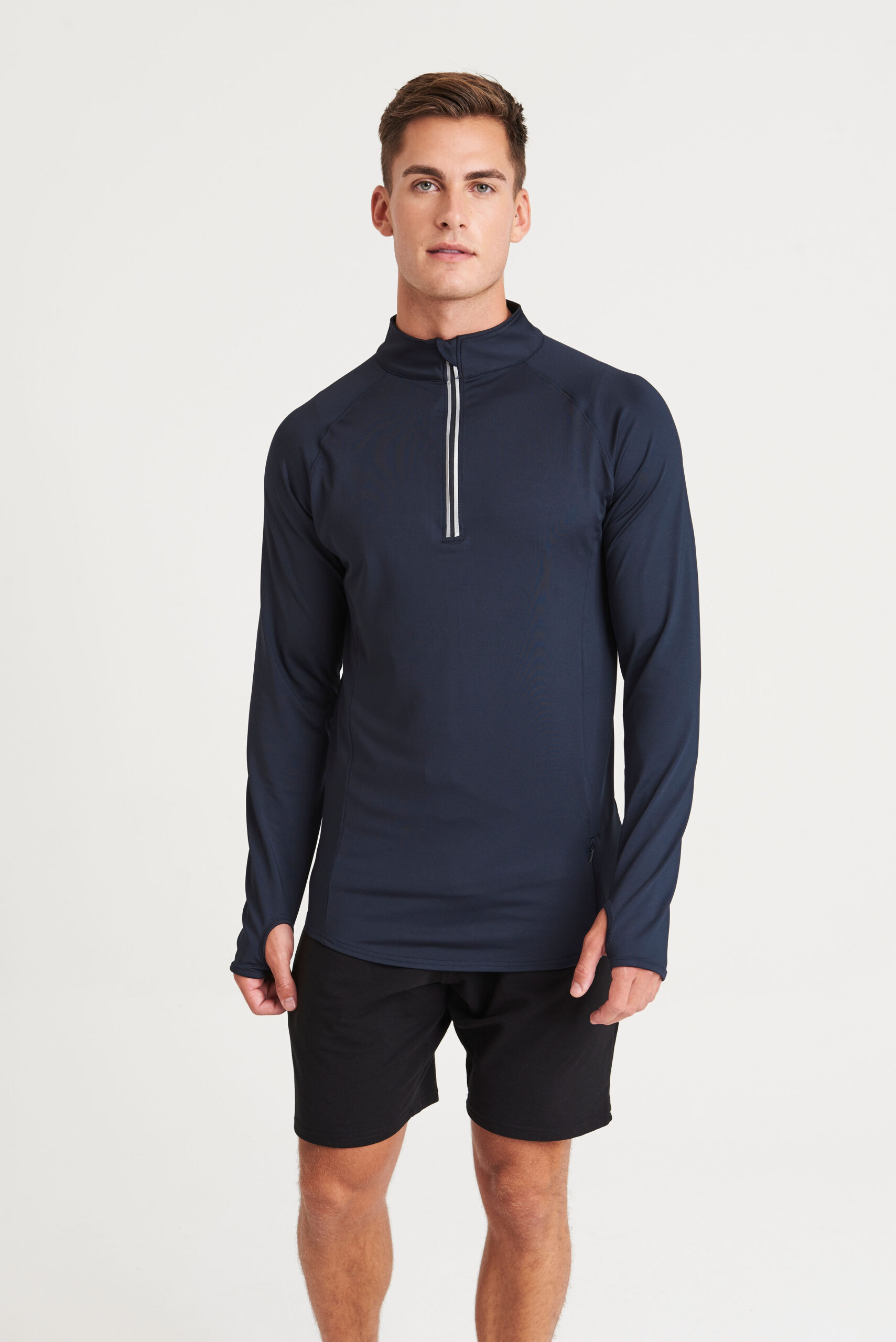 A model wearing a long sleeved half zip top in french navy with thumb holes.