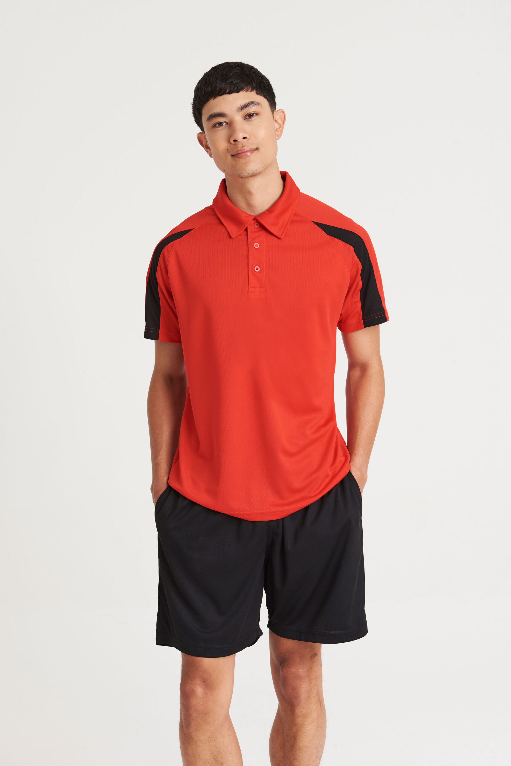 A model wearing a polo shirt in the shade fire red, with contrast panels in the shade jet black